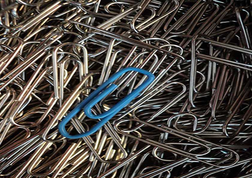 blue paper clip on top of hundreds of ordinary silver paperclips